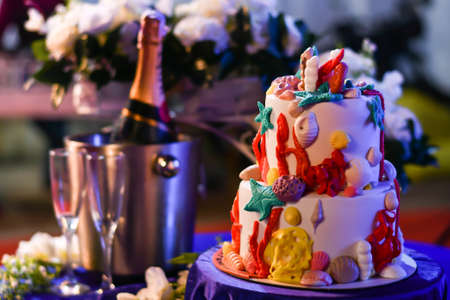 Ocean themed birthday cake with champagne and white flowers in the backgroundの写真素材