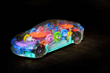 Transperent mechanical plastic toy model of a car with black background