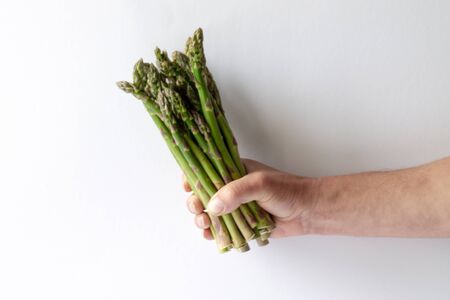 Asparagus in a man's hand on white background. To eat healthy food.の写真素材
