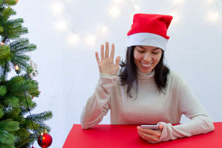 Christmas online congratulations. Smiling girl with a mobile phone in her handsの写真素材