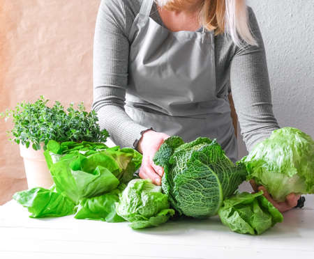 A womans hand holds a green salad in her hands.の写真素材
