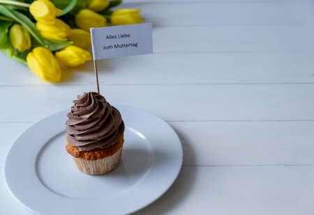 happy mothers day. Cupcake with chocolate cream and a bouquet of flowers.の写真素材