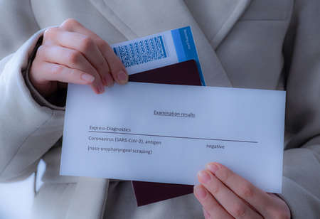 Girl holding passport, boarding passes and coronavirus test in her handsの写真素材