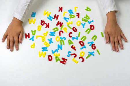 Colorful letters. The childs hands lay out colored letters on the table. Soon to school