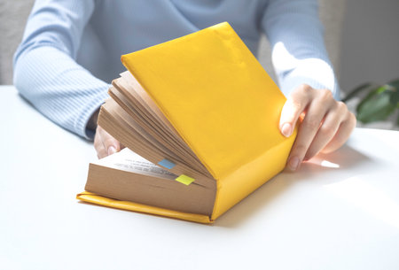 The girls hands are holding a yellow book. Education conceptの写真素材