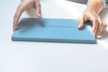 Girls hands holding a tablet in a case. Preparing to work on a tabletの写真素材
