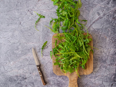 Fresh herbs arugula on a cutting board on the kitchen tableの写真素材