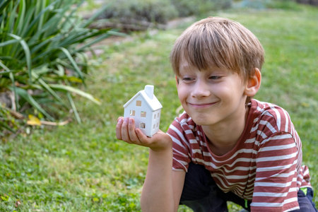boy holding a house model on his handの写真素材