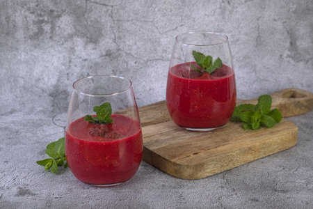 Raspberry smoothie garnished with fresh fruit and mintの写真素材