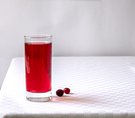 Cranberry juice in a glass on a table with a white tableclothの写真素材