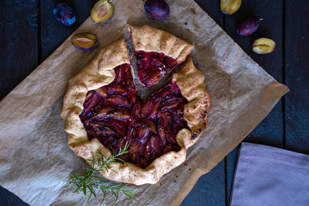 Galette with plums on a dark wood background. toning. selective focus on the plums in the galetteの写真素材