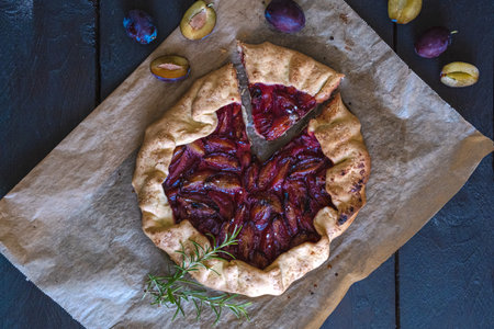 Galette with plums on a dark wood background. toning. selective focus on the plums in the galetteの写真素材