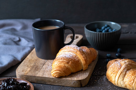 Coffee and croissant on a dark wooden background. French breakfast.の写真素材