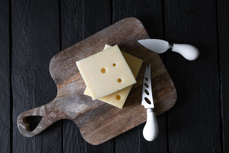 A piece of hard cheese on a wooden board. Top viewの写真素材