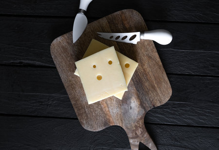 A piece of hard cheese on a wooden board. Top viewの写真素材