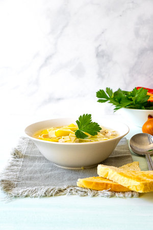 Chicken soup with noodles and vegetables in white bowlの写真素材