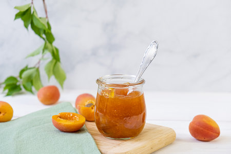 Homemade organic jam in glass jar and ripe apricots on wooden rustic tableの写真素材