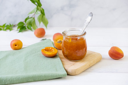 Homemade apricot jam in glass jar on kitchen white background. Summer harvest and canned food.の写真素材