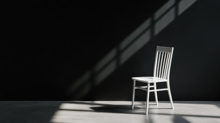 Studio-style shot of a white chair in a dark room, light forming sharp contoursの素材