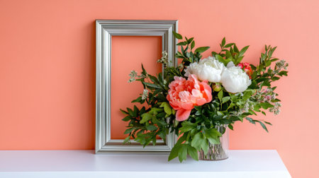 Classy floral art of peonies and greens arranged in silver frame against peachの素材