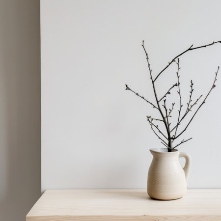 This minimalist still life showcases a delicate branch in a smooth ceramic vessel on a wooden table. The soft lighting emphasizes tranquility and simplicity.の素材