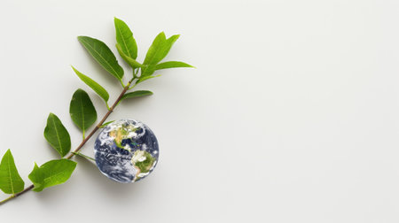 This creative image features a green leaf branch holding a globe representing Earth, symbolizing the harmony between nature and sustainability while promoting environmental awareness.の素材