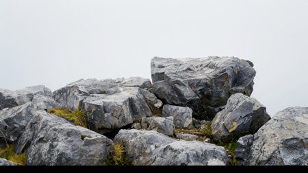 A gray rock formation stands prominently amidst a foggy atmosphere, showcasing rugged stone textures and patches of grass, ideal for nature-themed projects.の素材