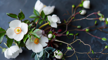 A stunning arrangement of delicate white flowers and green leaves set against a dark surface. This composition embodies natural beauty and elegance.の素材