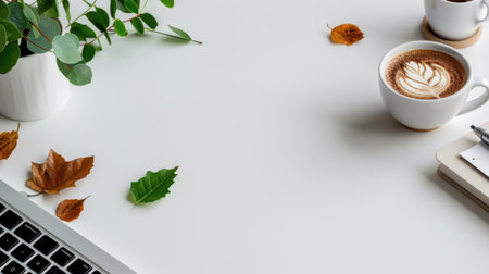 This image captures a cozy autumn workspace featuring a steaming coffee cup and decorative leaves on a minimalist white desk, perfect for work or relaxation.の素材