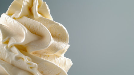 A close-up view of creamy soft serve ice cream presented in a beautiful swirl shape. The minimalist background emphasizes the dessert's smooth texture and inviting appearance, perfect for food-related concepts.の素材