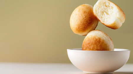 This captivating image features three freshly baked rolls expertly balancing on a white bowl, set against a soft, neutral background, perfect for culinary inspiration.の素材