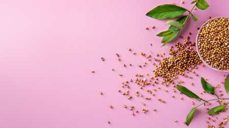 A vibrant arrangement of fresh yellow mustard seeds and green leaves on a soft pink background, ideal for culinary and food-related projects.の素材