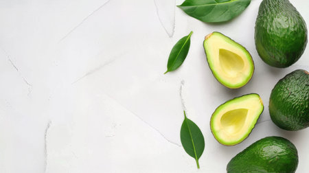 A beautiful arrangement of fresh avocados on a white background with green leaves. Perfect for highlighting health, nutrition, and culinary creativity.の素材