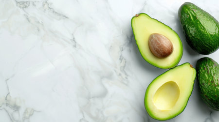 Aesthetic view of fresh avocado halves displayed on a smooth marble surface, showcasing the creamy texture and vibrant green color, ideal for nutrition photography.の素材