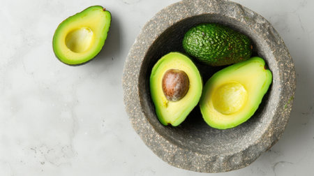This image showcases fresh avocados in a stone bowl placed on a marble surface. Ideal for highlighting healthy cooking, nutrition themes, and gourmet recipes.の素材