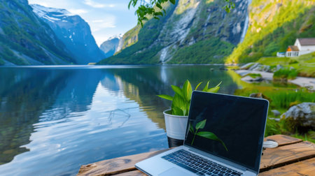 A serene remote work environment featuring a laptop set against a breathtaking lake surrounded by lush mountains, promoting tranquility and inspiration.の素材