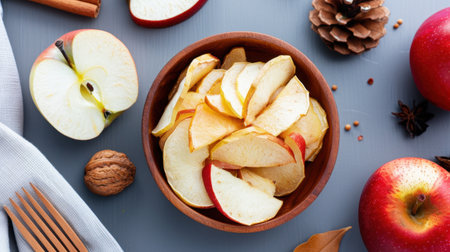 A visually appealing composition of freshly sliced apples arranged in a wooden bowl, surrounded by natural elements and spices, perfect for autumn cooking.の素材