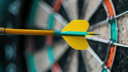 Close-up shot of a bright yellow dart embedded in the bullseye of a dartboard, illustrating focus and precision in a competitive game setting.の素材