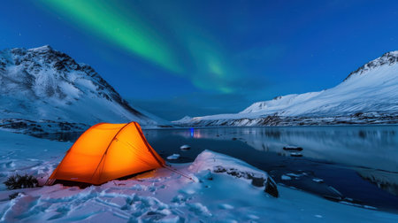 A vibrant orange tent stands brightly against the serene backdrop of snow-covered mountains and a tranquil lake, illuminated by dancing northern lights.の素材