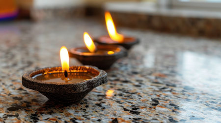 Three clay diyas emitting warm, flickering flames are placed on a smooth marble surface, creating a serene and inviting atmosphere in soft natural lighting.の素材