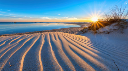 Captivating view of serene sunset above sandy dunes, showcasing vibrant colors and calm reflections in tranquil waters. Ideal for nature lovers.の素材