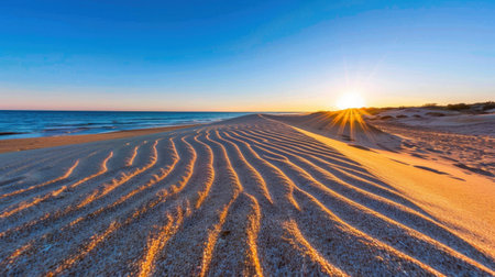 A picturesque sunset illuminates a sandy beach with gentle ripples, creating a tranquil setting by the ocean. The warm colors evoke serenity.の素材