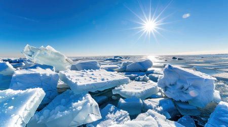 A stunning view of icebergs scattered across a frozen landscape, illuminated by the bright sunlight under a clear blue sky. This breathtaking scene captures the beauty of nature in winter.の素材
