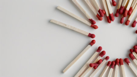 This image features a creative arrangement of matches radiating outwards on a minimalistic white background, showcasing vibrant red tips. Perfect for design projects.の素材
