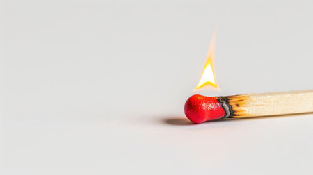 A close-up image of a matchstick being ignited, showcasing the vibrant red tip and emerging flame against a clean background.の素材