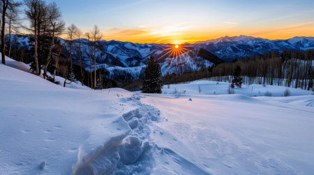 A breathtaking winter landscape featuring snow-covered mountains illuminated by the warm glow of sunrise. The scene captures a peaceful and serene atmosphere, with a well-defined trail leading through pristine snow. Ideal for nature enthusiasts and outdoor lovers.の素材