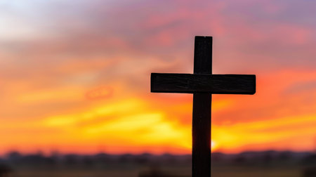 A captivating silhouette of a wooden cross against a vibrant sunset sky, embodying themes of faith and spirituality. Soft clouds enhance the serene backdrop.の素材