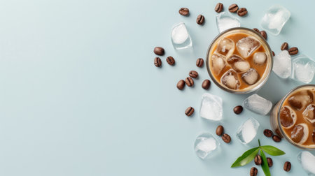 Indulge in a refreshing iced coffee beverage featuring rich flavors, ice cubes, and coffee beans arranged aesthetically on a soft blue background.の素材