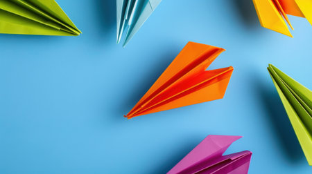 This vibrant image features an array of colorful paper airplanes positioned on a soft blue background, ideal for creative projects, arts, and crafts.の素材