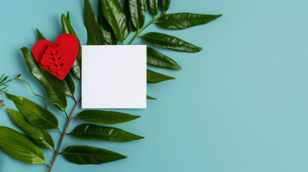 A captivating composition featuring vibrant green leaves paired with a red heart and a blank square for text on a soft blue background, ideal for creative projects.の素材
